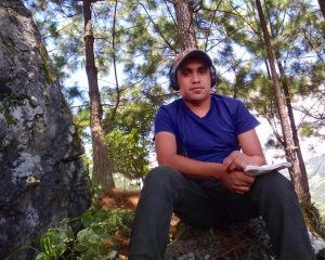 Dario Ba Xuc, Bible translator, sits on a rock on a mountain in Guatemala.